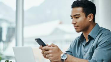 Dark haired man in a blue shirt using a phone